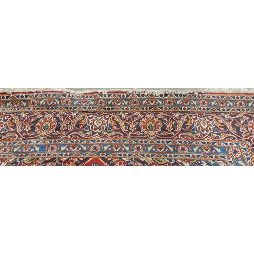 2142 - A RED GROUND KESHAN RUGwith all over floral foliate design, dark blue central medallion, matching sp... 