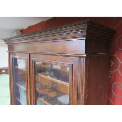 30 - A Victorian oak glazed bookcase with moulded cornice over pair of glazed doors over two drawers over... 