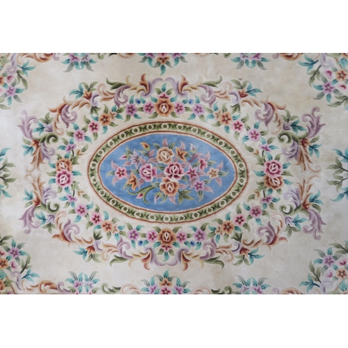 86 - A 20th century cream ground Oriental floral rug with blue oval central medallion, floral spandrel an... 