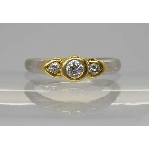 717 - A platinum and 18ct gold three stone diamond ring, two of the brilliant cuts set in pear shaped beze... 