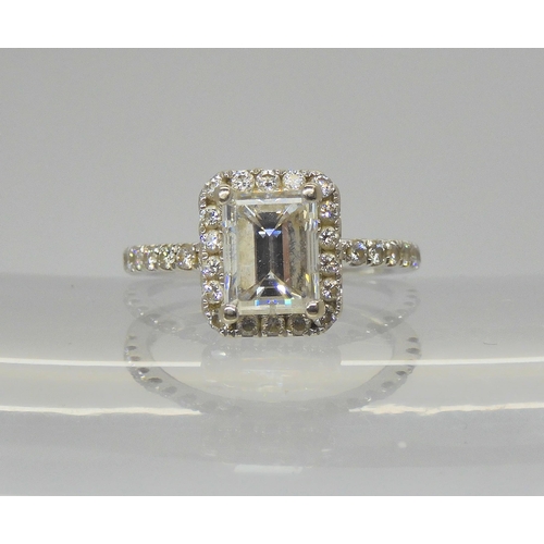 A 14k white gold substantial diamond ring, set with an estimated approx 1.40ct step cut diamond, with further brilliant cut diamonds set to the bezel and shoulders, at estimated approx 0.25cts taking the total diamond content to £1.65cts. Finger size I1/2, weight 2.7gms