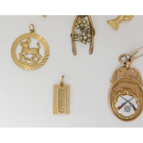 801 - Three 9ct Nefertiti head pendants, a 9ct medal, a gold ingot, a Leo medal and a part wishbone brooch... 