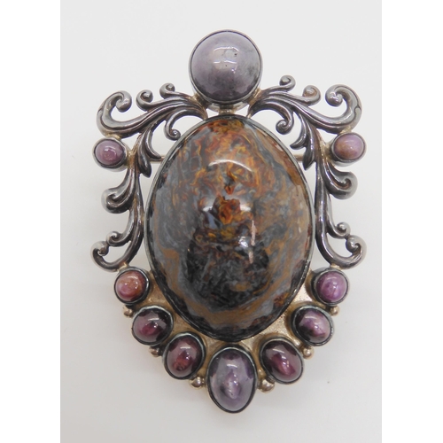 891 - A silver pendant brooch set with star rubies and a large blue and gold tigers eye specimen stone cal... 