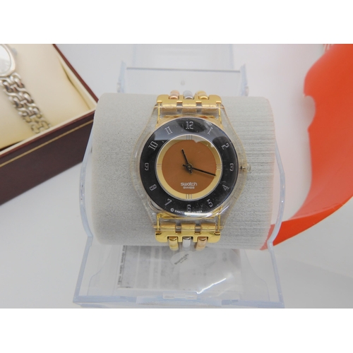 896 - A Swatch watch with three coloured golden strap and mirrored dial in original packaging, together wi... 