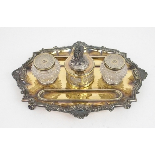 2474 - A GEORGE IV SILVER GILT INKSTANDof oblong lobed form, with a cast scrolling shellwork border, on fou... 