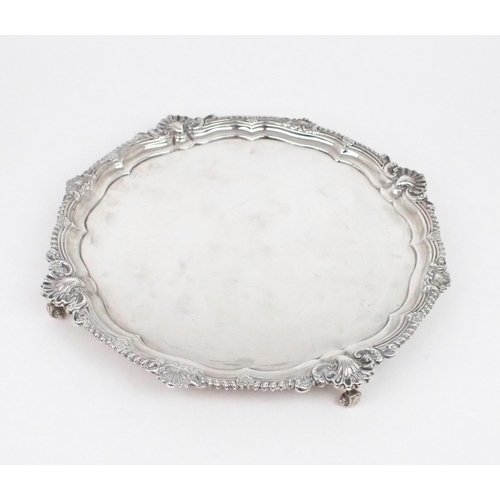 2487 - AN EDWARDIAN SILVER SALVERof plain form, with a gadrooned shellwork border, on four scroll feet, by ... 