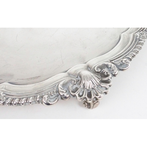 2487 - AN EDWARDIAN SILVER SALVERof plain form, with a gadrooned shellwork border, on four scroll feet, by ... 