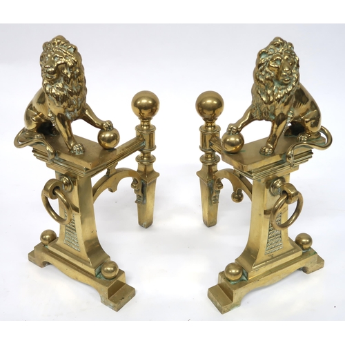 2052 - A PAIR OF EARLY 20TH CENTURY CAST BRASS FIRE DOGSmounted with figural lions, 46cm high x 23cm wide x... 