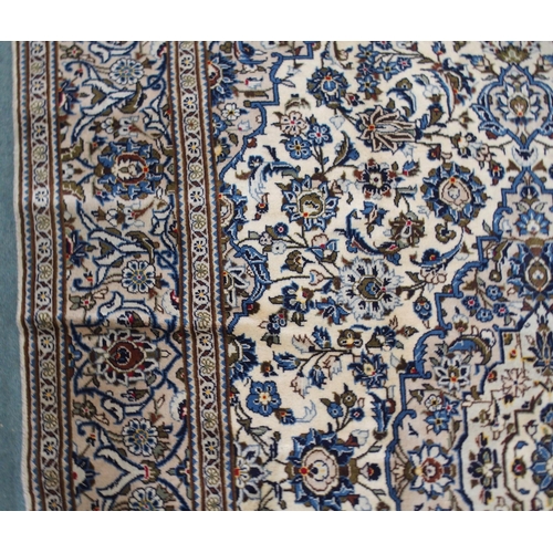 2133 - A CREAM GROUND KASHAN RUGwith blue diamond central medallion, matching spandrels and flower head bor... 