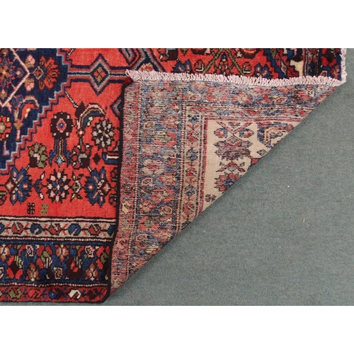 2138 - A TERRACOTTA GROUND HAMADAN RUGwith dark blue central medallion, cream spandrels and blue floral bor... 