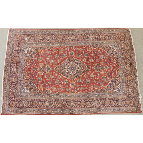 2142 - A RED GROUND KESHAN RUGwith all over floral foliate design, dark blue central medallion, matching sp... 