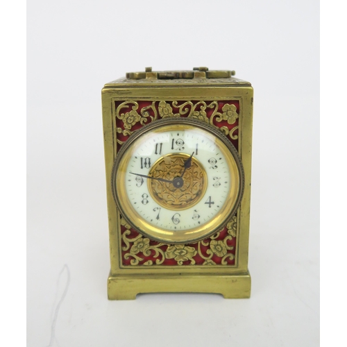 2179 - A PIERCED BRASS TIMEPIECEwith red lining, the white enamel dial ring with Arabic numerals, 12cm high... 