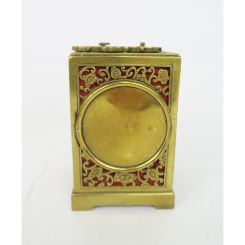 2179 - A PIERCED BRASS TIMEPIECEwith red lining, the white enamel dial ring with Arabic numerals, 12cm high... 