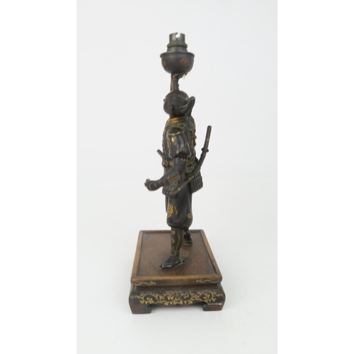 2366 - A JAPANESE BRONZE SAMURAI LAMP Standing and wearing battle dress, decorated with family Mon crests a... 