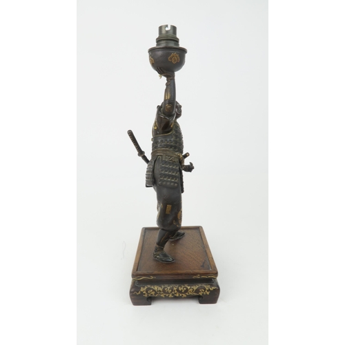 2366 - A JAPANESE BRONZE SAMURAI LAMP Standing and wearing battle dress, decorated with family Mon crests a... 