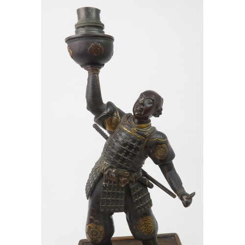 2366 - A JAPANESE BRONZE SAMURAI LAMP Standing and wearing battle dress, decorated with family Mon crests a... 