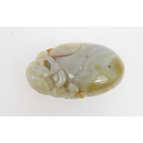 2419 - A CHINESE POLISHED AGATE PEBBLE Carved with a grotesque animal holding a fruiting branch, 8cm high... 