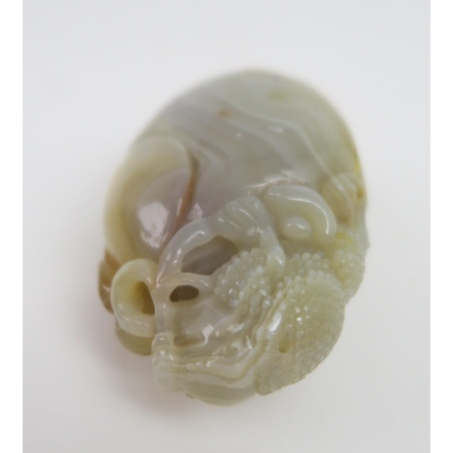 2419 - A CHINESE POLISHED AGATE PEBBLE Carved with a grotesque animal holding a fruiting branch, 8cm high... 