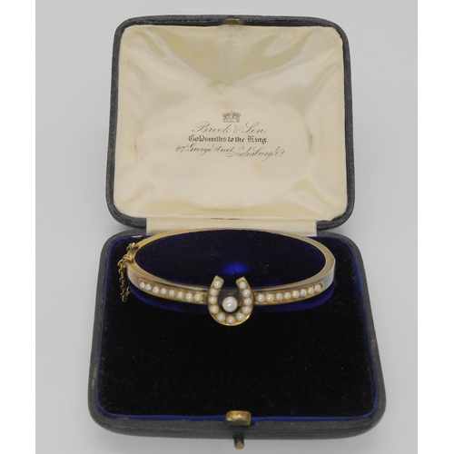 2709 - A PEARL SET HORSESHOE BANGLEmounted in yellow metal, with inscription to the inner shank dated 1907.... 