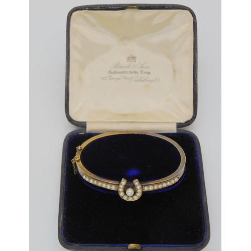 2709 - A PEARL SET HORSESHOE BANGLEmounted in yellow metal, with inscription to the inner shank dated 1907.... 