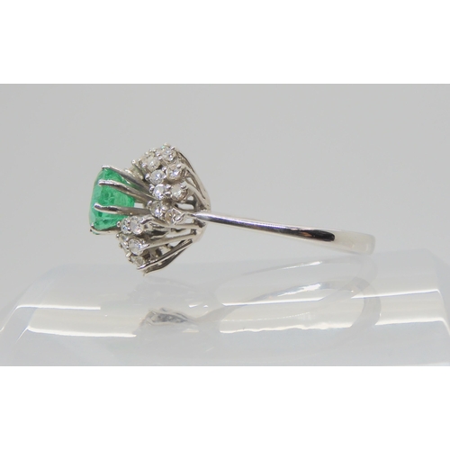 2712 - AN EMERALD & DIAMOND CLUSTER RINGset with a 6.1mm x 6.4mm x 4.4mm step cut emerald, and estimate... 