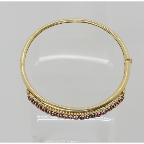2727 - A RUBY BANGLEwith a yellow metal traditional claw set mount, the rubies taper in size from largest 4... 