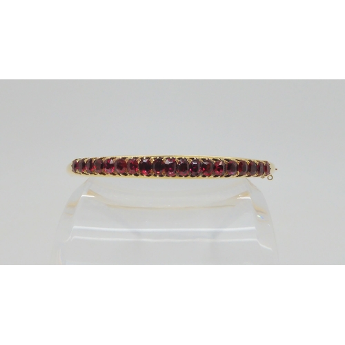 2727 - A RUBY BANGLEwith a yellow metal traditional claw set mount, the rubies taper in size from largest 4... 