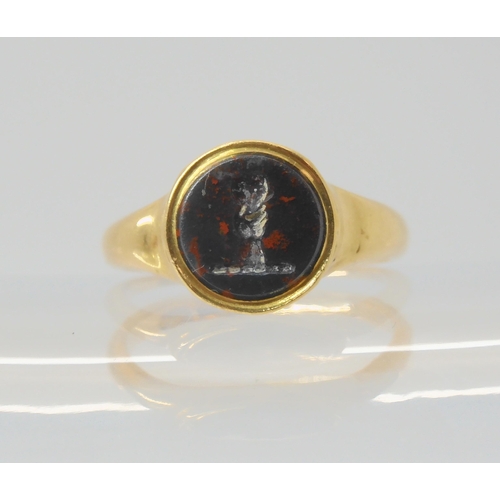 2794 - AN 18CT GOLD INTAGLIO SIGNET RINGset with an intaglio carved bloodstone, depicting a hand holding a ... 