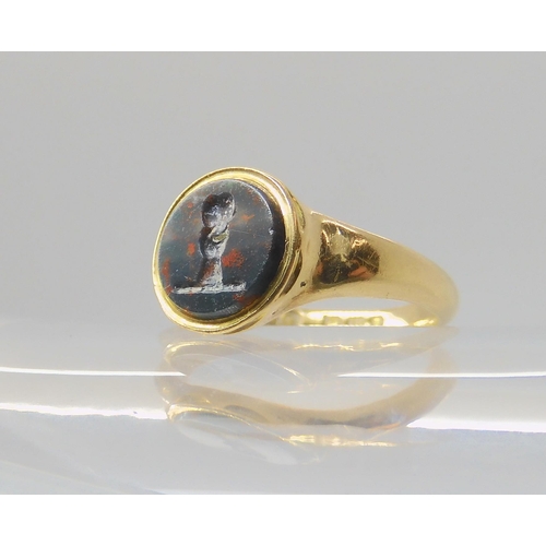 2794 - AN 18CT GOLD INTAGLIO SIGNET RINGset with an intaglio carved bloodstone, depicting a hand holding a ... 