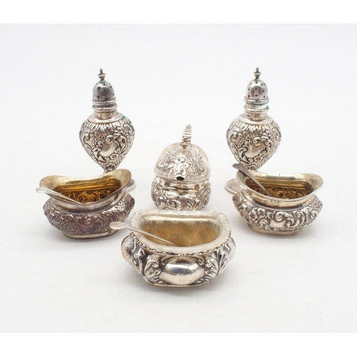 411 - An Edwardian silver five piece condiment set, the bodies with repousse scrolling foliate decoration ... 