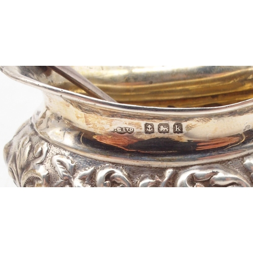 411 - An Edwardian silver five piece condiment set, the bodies with repousse scrolling foliate decoration ... 