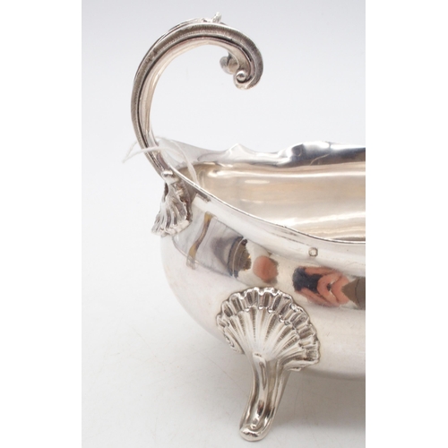 440 - A French silver sauce boat, with a shaped rim, a flying shell and scroll handle, supported on three ... 