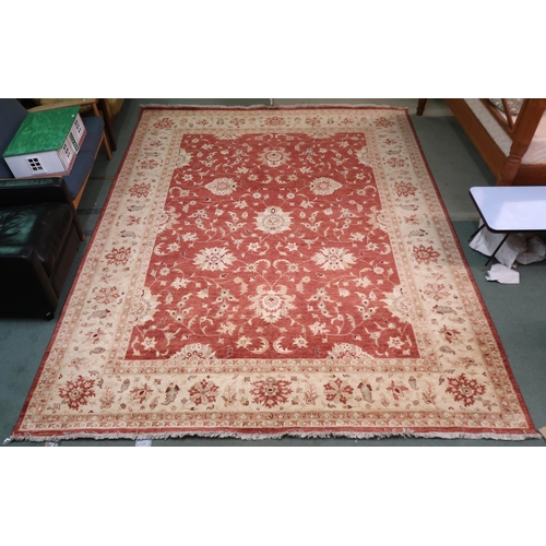 64 - A red ground Pakistani Zeigler rug with all-over floral design and cream flower head borders, 355cm ... 