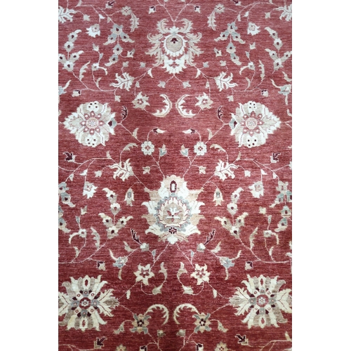 64 - A red ground Pakistani Zeigler rug with all-over floral design and cream flower head borders, 355cm ... 