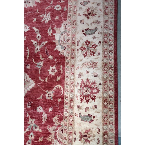 64 - A red ground Pakistani Zeigler rug with all-over floral design and cream flower head borders, 355cm ... 