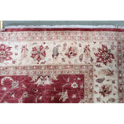 64 - A red ground Pakistani Zeigler rug with all-over floral design and cream flower head borders, 355cm ... 