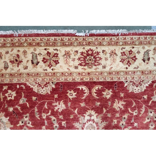 64 - A red ground Pakistani Zeigler rug with all-over floral design and cream flower head borders, 355cm ... 