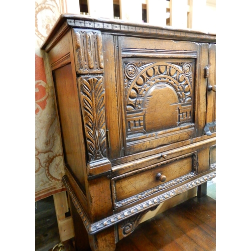 83 - A 20th century stained oak court cabinet with pair of carved cabinet doors over pair of drawers on t... 