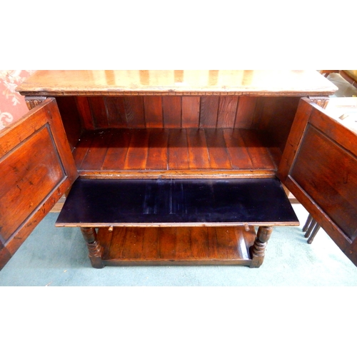 83 - A 20th century stained oak court cabinet with pair of carved cabinet doors over pair of drawers on t... 