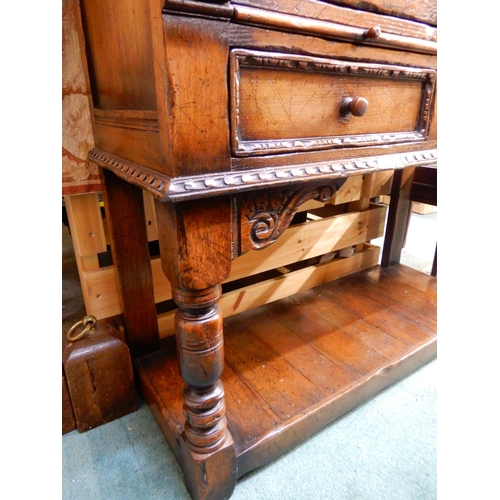 83 - A 20th century stained oak court cabinet with pair of carved cabinet doors over pair of drawers on t... 