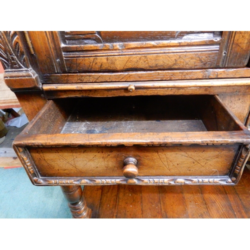 83 - A 20th century stained oak court cabinet with pair of carved cabinet doors over pair of drawers on t... 