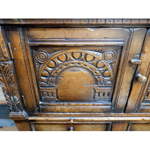 83 - A 20th century stained oak court cabinet with pair of carved cabinet doors over pair of drawers on t... 