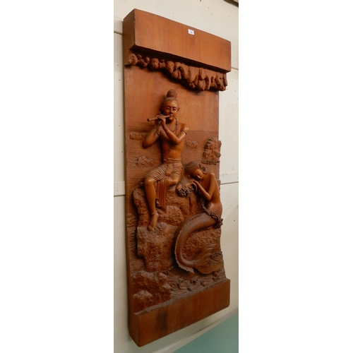 95 - A 20th century hardwood wall sculpture of a piper and a mermaid, 162cm high x 65cm wide