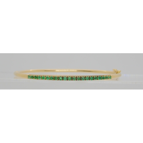 765 - A 14k gold bangle set with emeralds, inner dimensions 5.7cm x 5.2cm, weight 5.4gms