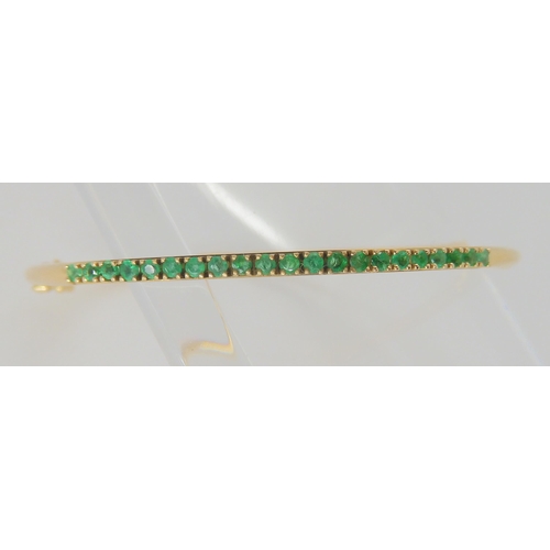 765 - A 14k gold bangle set with emeralds, inner dimensions 5.7cm x 5.2cm, weight 5.4gms