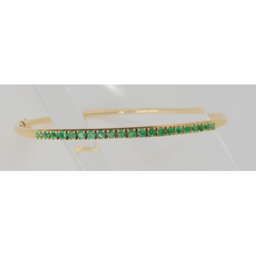 765 - A 14k gold bangle set with emeralds, inner dimensions 5.7cm x 5.2cm, weight 5.4gms