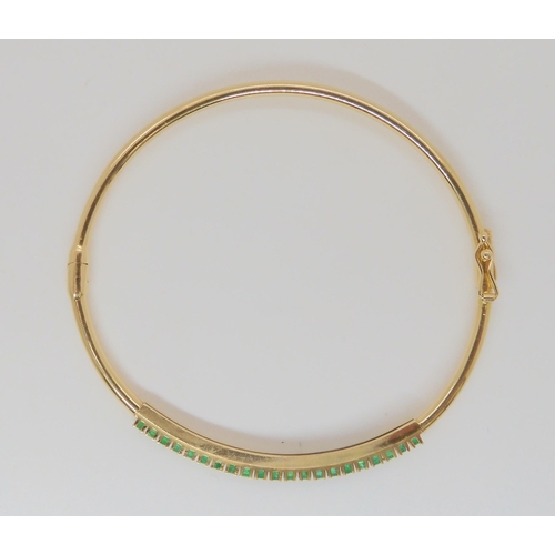 765 - A 14k gold bangle set with emeralds, inner dimensions 5.7cm x 5.2cm, weight 5.4gms