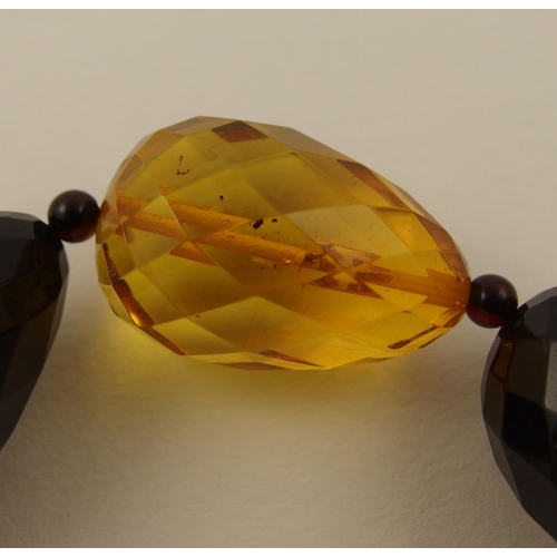 104 - Item 9. A long necklace of egg shaped yellow and dark cherry amber coloured beads