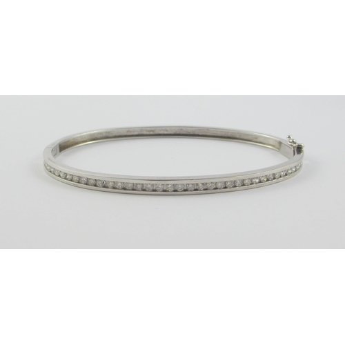 116 - A channel set diamond bangle in 9ct white gold  forty diamonds of approx 0.8cts total weight. With s... 