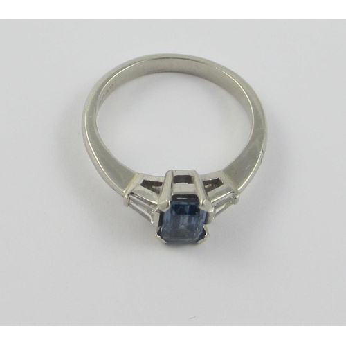 117 - A platinum sapphire and diamond ring  set with a claw set emerald cut sapphire  and tapered baguette... 